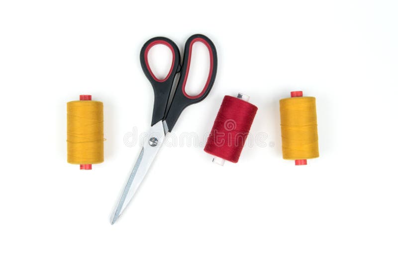 Sewing accessories and tools. Red sewing threads, black scissors, yellow  measuring tape and thimble on a white background. Stock Photo