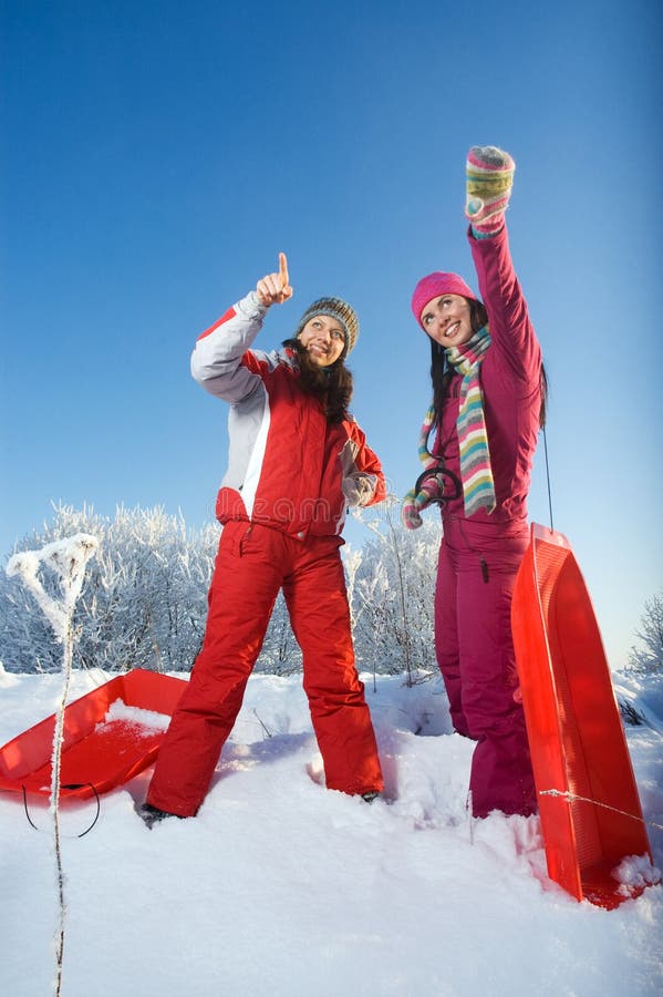 Two young beautiful girls with sledges