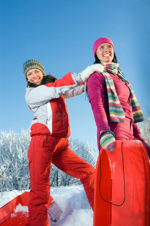 Two young beautiful girls with sledges