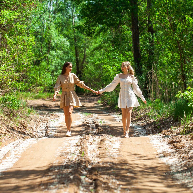 Two chicks in pretty summer outfits walk across the street