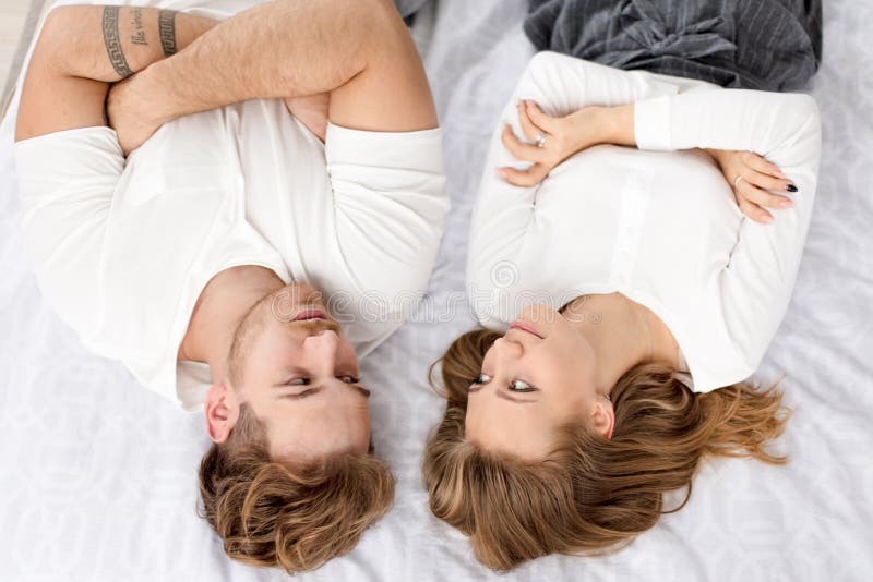 Two young blond people lying on the bed with crossed arms and looking at each other stock images Two young blond people lying on the bed with crossed arms and looking at each other stock images
