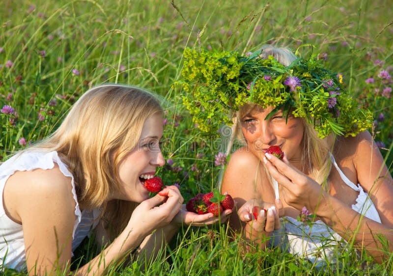 Two young blond women eating strawberries