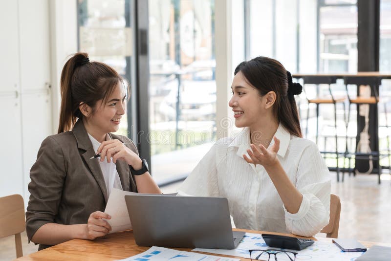 Young businesswoman and colleague collaboration in a modern office environment, discussing ideas and working together on stock photo