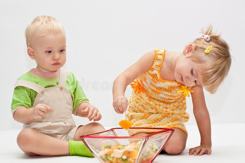 Two young children eating fruits