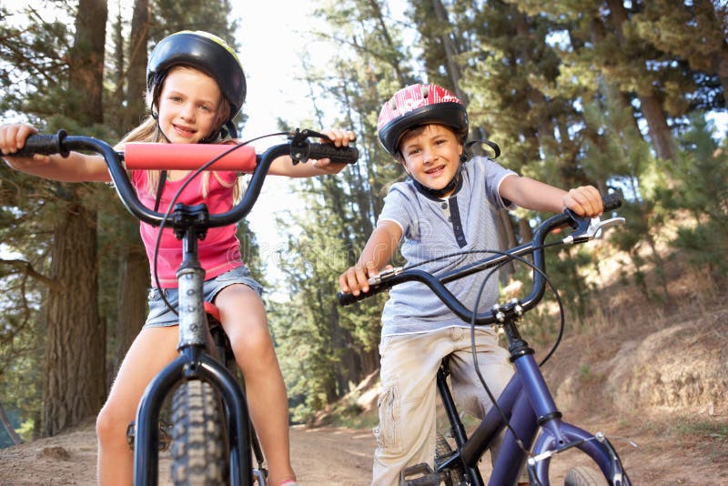 Two young children enjoying a bike ride smiling at camera