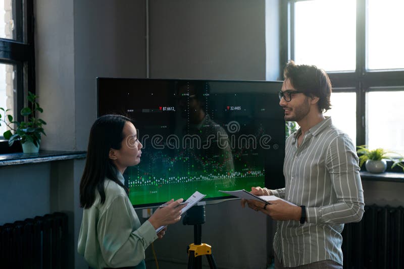 Two young confident analysts discussing interactive financial data royalty free stock photography
