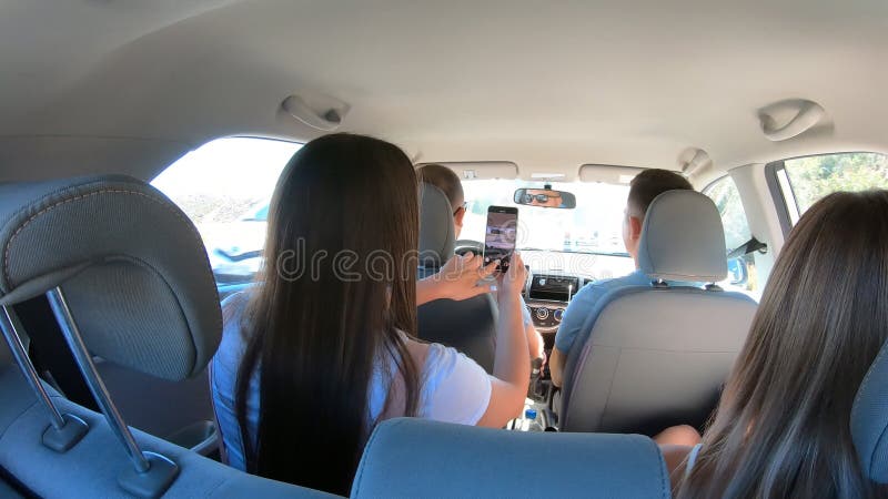 Two young couple traveling by car together. Men and women sitting in car`s interior during the road trip. Friends