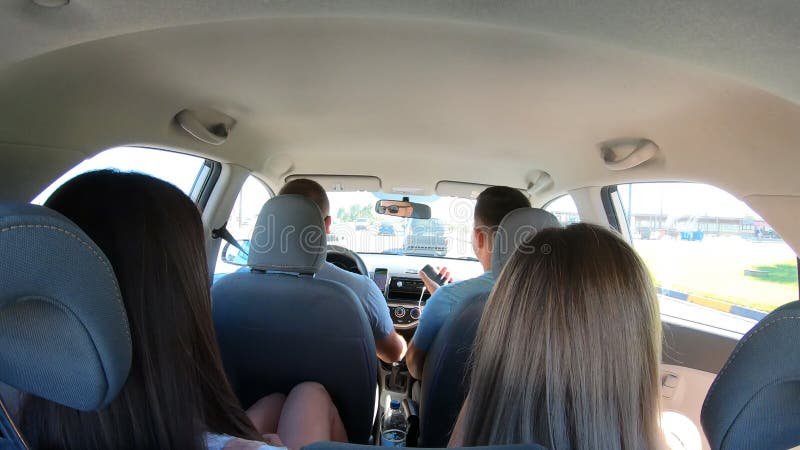 Two young couple traveling by car together. Men and women sitting in car`s interior during the road trip. Friends