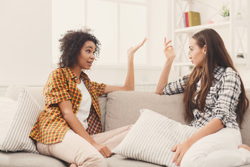 Two young female friends conversing at home