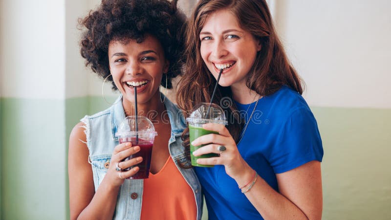 Two young friends drinking fresh fruit juice