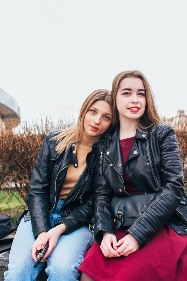 Two young girl friends sitting together and having fun in city .Outdoors. lifestyle.