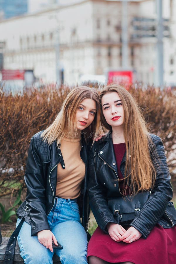 Two young girl friends sitting together and having fun in city .Outdoors. lifestyle.