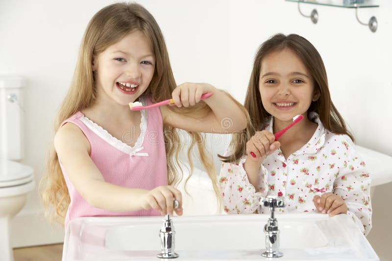 Two Young Girls Brushing Teeth at Sink