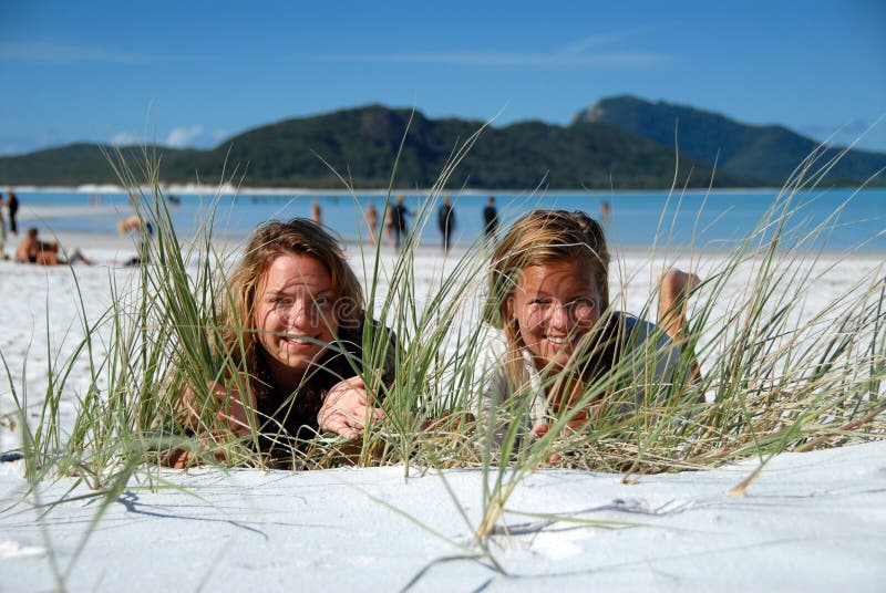 Two young girls hiding behind grass on beach