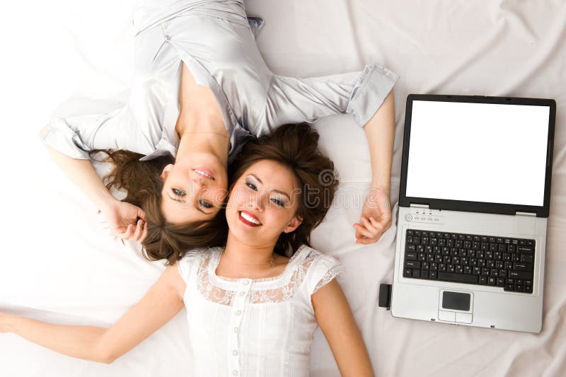 Two Young girls with laptop lying on the floor