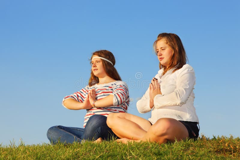 Two young girls meditate and reflect at grass stock photos Two young girls meditate and reflect at grass stock photos