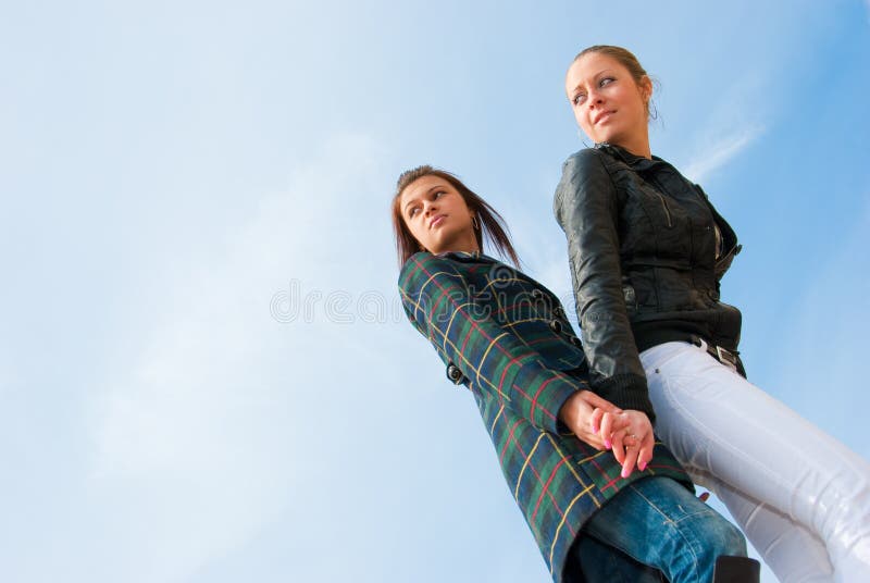 Two young girls portrait over sky