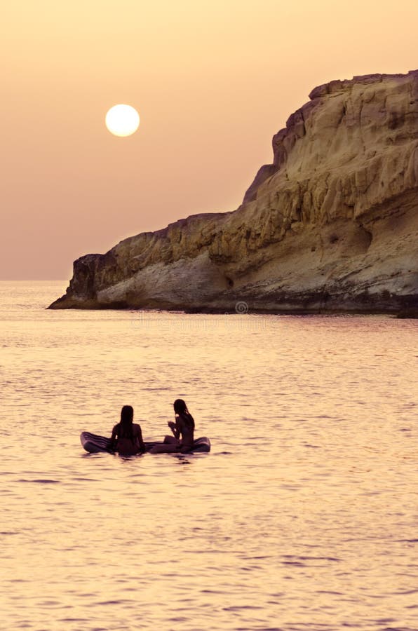 Two young girls relax on their inflatable, enjoying the sunset.