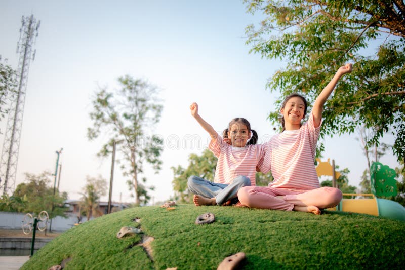 Two young girls are sitting on a grassy hill royalty free stock image