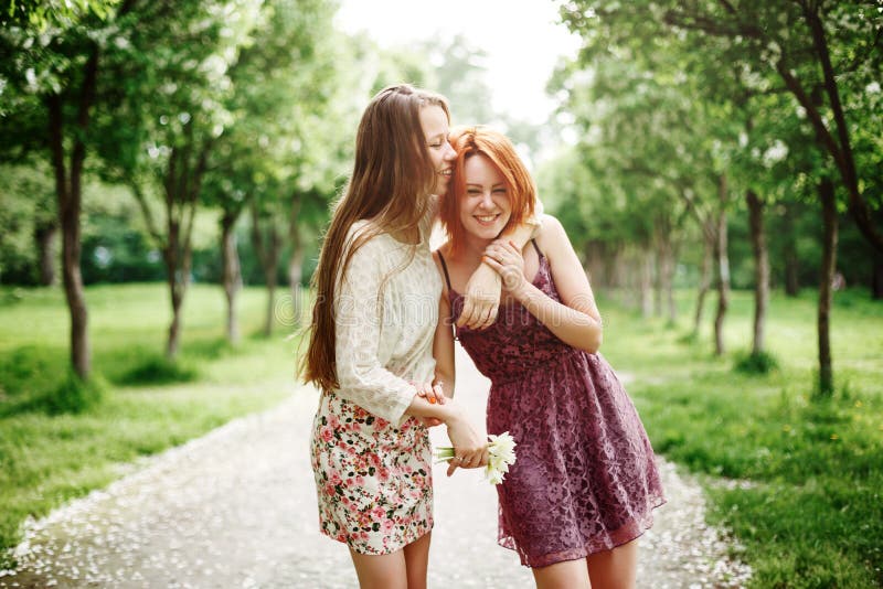 Two Young Happy Girls Having Fun in the Summer Park. Best Friends Laughing and Embracing. Two Young Happy Girls Having Fun in the Summer Park. Best Friends Laughing and Embracing.