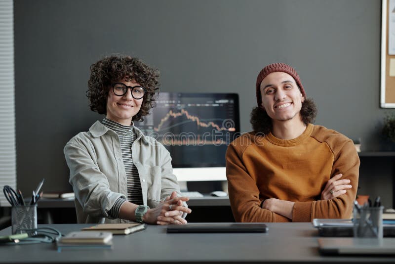 Two young intercultural managers in casualwear sitting by workplace royalty free stock images