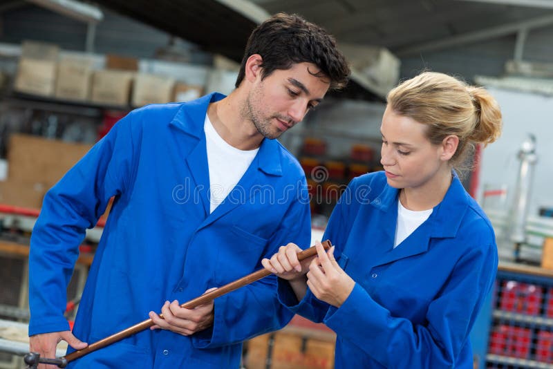 Two Young Manual Workers Inspecting Copper Pipe Stock Photo Image of
