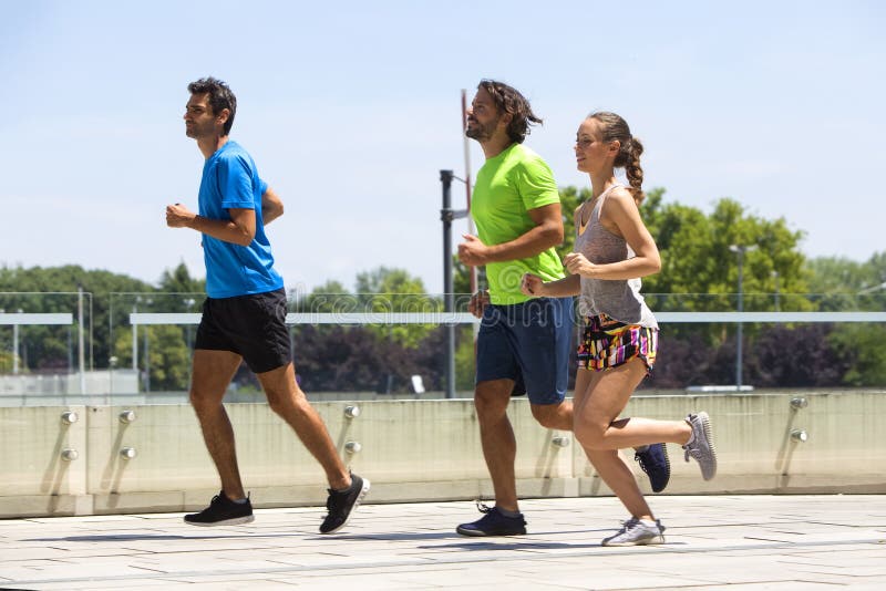 Two Young Men and Woman Running in Urban Enviroment Stock Image - Image ...