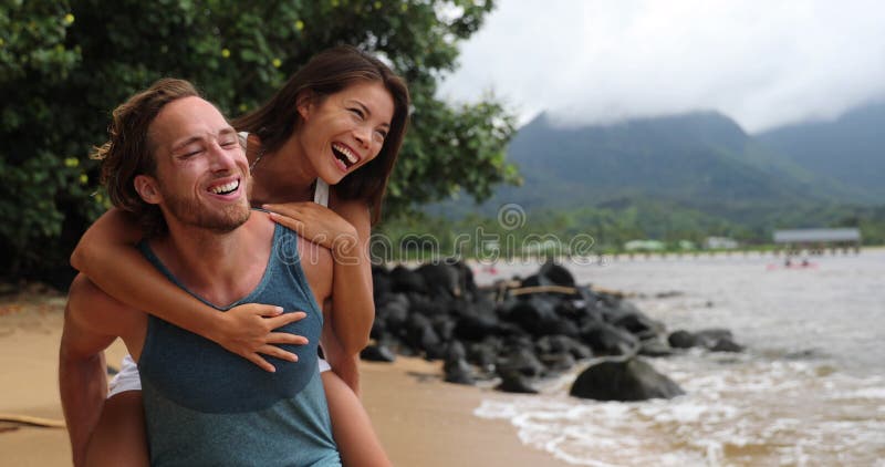 Two young people playing having fun laughing in love - couple piggybacking