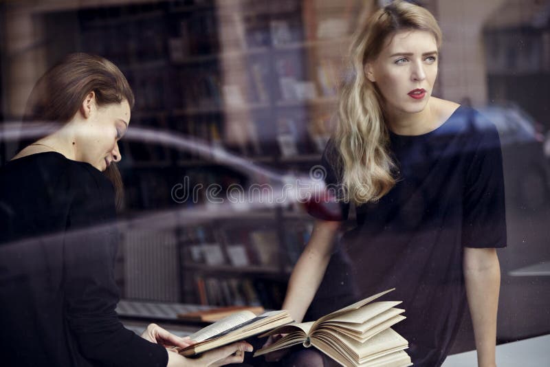Two young professional women in a library reading books. Education concept stock photo Two young professional women in a library reading books. Education concept stock photo