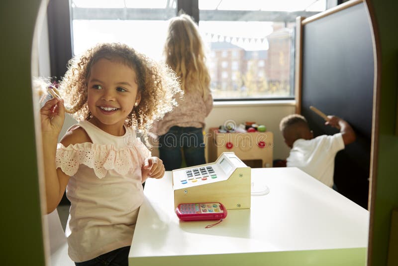 Two young schoolgirls and a boy playing together in a playhouse at infant school, backlit royalty free stock image Two young schoolgirls and a boy playing together in a playhouse at infant school, backlit royalty free stock image