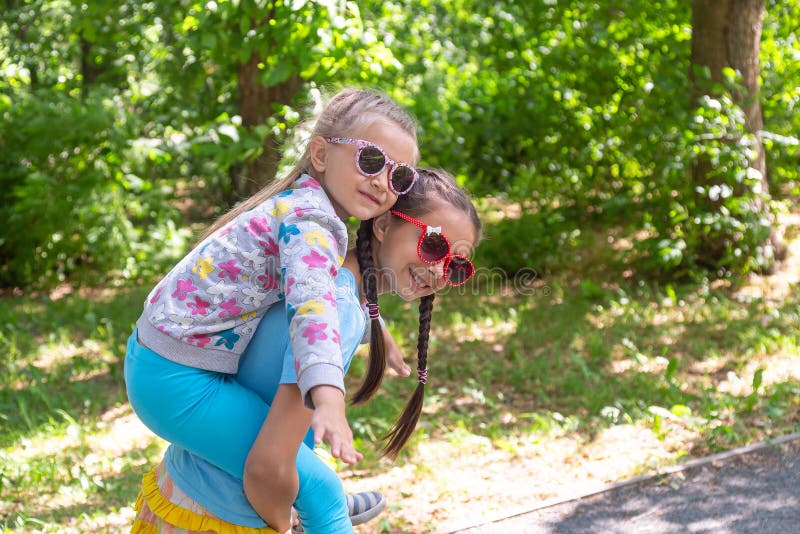 Happy adorable little girl on a piggy back ride with her elder sister