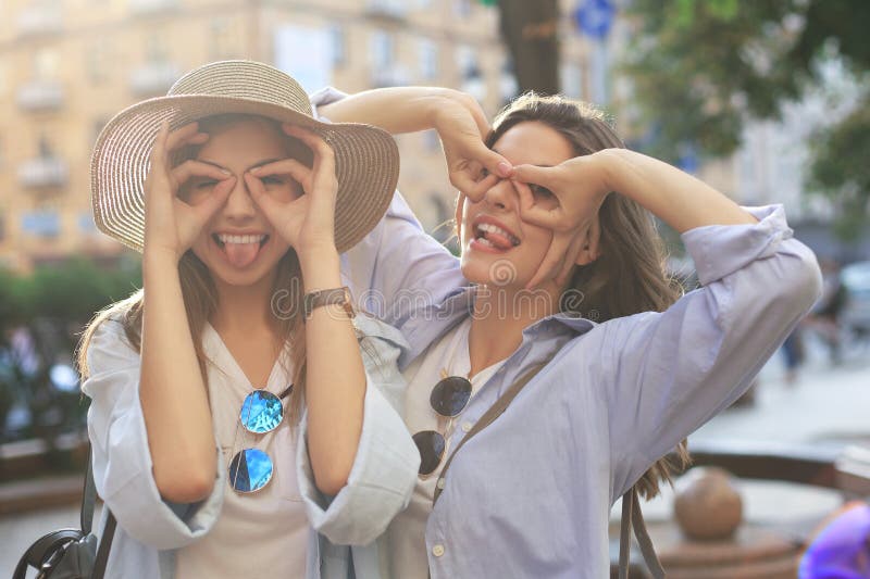 Two young smiling hipster women in summer clothes posing on street.Female showing positive face emotions stock photos Two young smiling hipster women in summer clothes posing on street.Female showing positive face emotions stock photos
