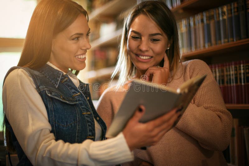 Two young students girl in library reading book.