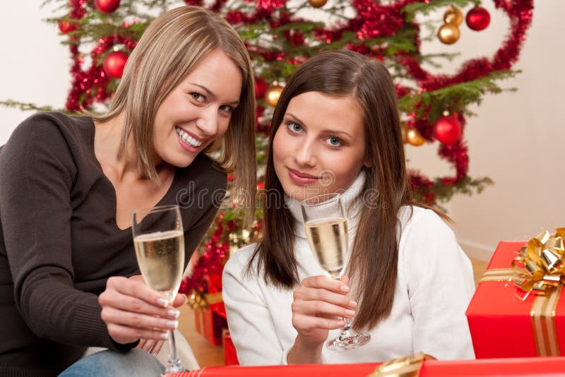 Two young woman with champagne and Christmas tree