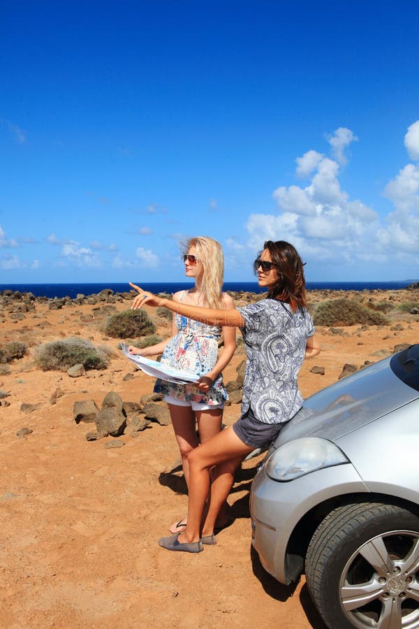 Two young women with car look at map