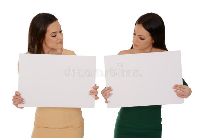Two young smiling women holding two pieces of blank paper, looking down on papers royalty free stock image Two young smiling women holding two pieces of blank paper, looking down on papers royalty free stock image