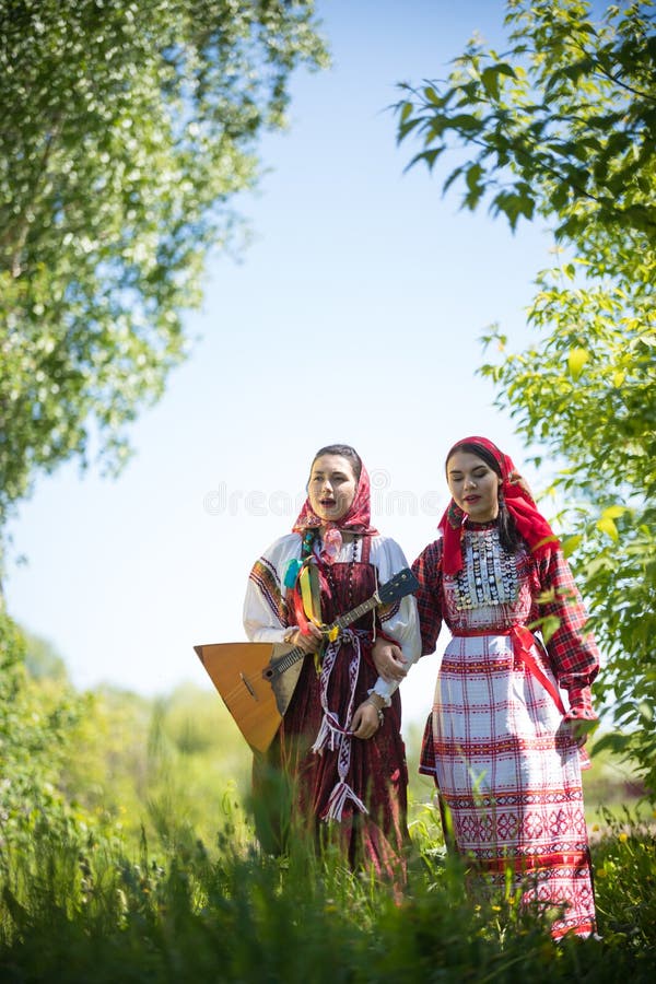 Young smiling woman in traditional russian clothes stands on a