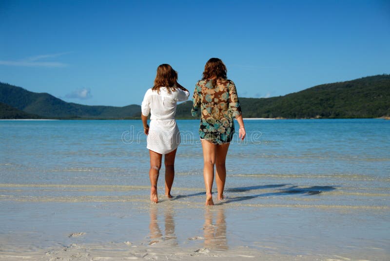 Two young women walking away to sea