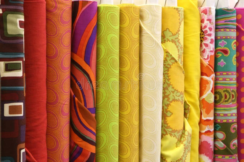 Close up of bold colorful bolts of quilt fabric in yellows oranges greens. Close up of bold colorful bolts of quilt fabric in yellows oranges greens
