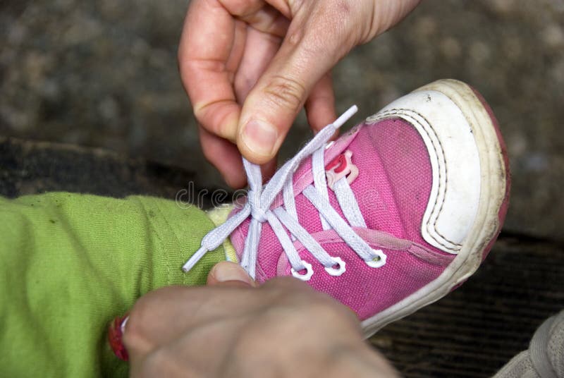 A mother helps her little daughter tying shoes. A mother helps her little daughter tying shoes