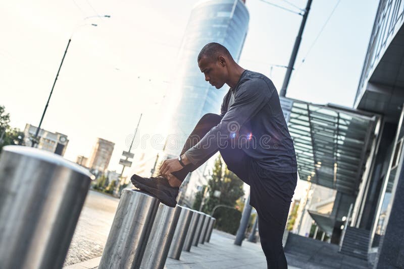 Tying shoelaces. Sporty african runner tying shoelace and getting ready for run outside. Health and sport concepts royalty free stock image Tying shoelaces. Sporty african runner tying shoelace and getting ready for run outside. Health and sport concepts royalty free stock image