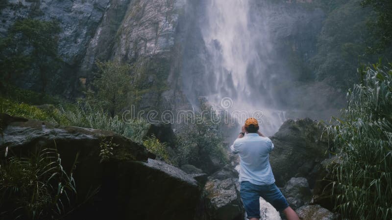 Tylnego widoku młody szczęśliwy turystyczny mężczyzna bierze smartphone fotografii na wolności scenicznego Sri Lanka tropikalna d