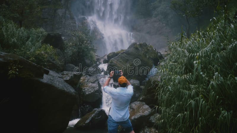 Tylnego widoku podróży z podnieceniem szczęśliwy męski blogger bierze smartphone wideo przy sceniczną Sri Lanka dżungli tropikaln