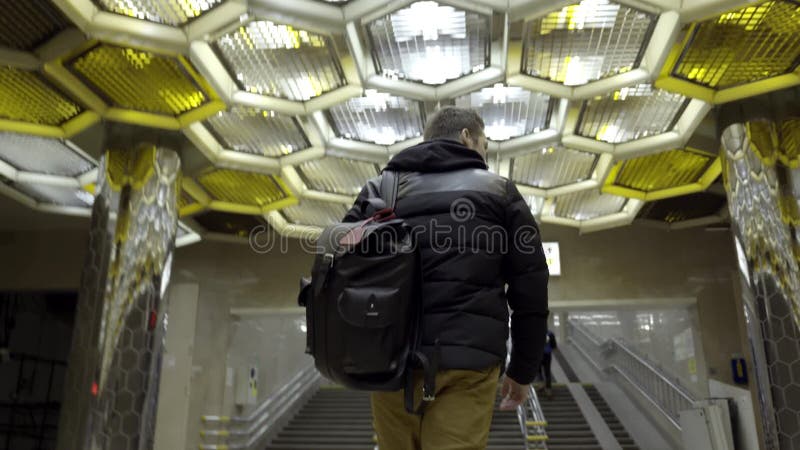 Tylni widok młodego człowieka odprowadzenie w metrze akcja Podróżnik iść z plecakiem na metrze na tle projektant