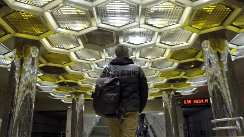 Tylni widok młodego człowieka odprowadzenie w metrze akcja Podróżnik iść z plecakiem na metrze na tle projektant