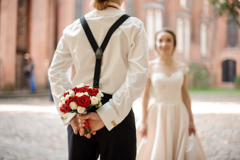 Tylny widok af fornal trzyma ślubnego bukiet dla jego panny młodej zdjęcie royalty free Tylny widok af fornal trzyma ślubnego bukiet dla jego panny młodej zdjęcie royalty free