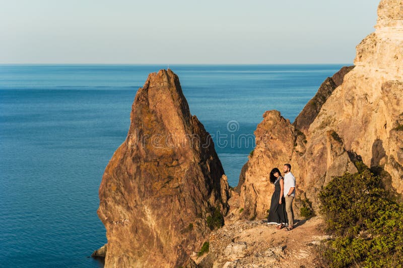 Type et fille à la mer étreignant au bord de la falaise image stock Type et fille à la mer étreignant au bord de la falaise image stock