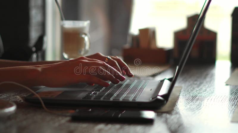 type femelle des mains 4k sur le clavier d'ordinateur portable touchant le touchpad avec le téléphone intelligent de doigts se tr