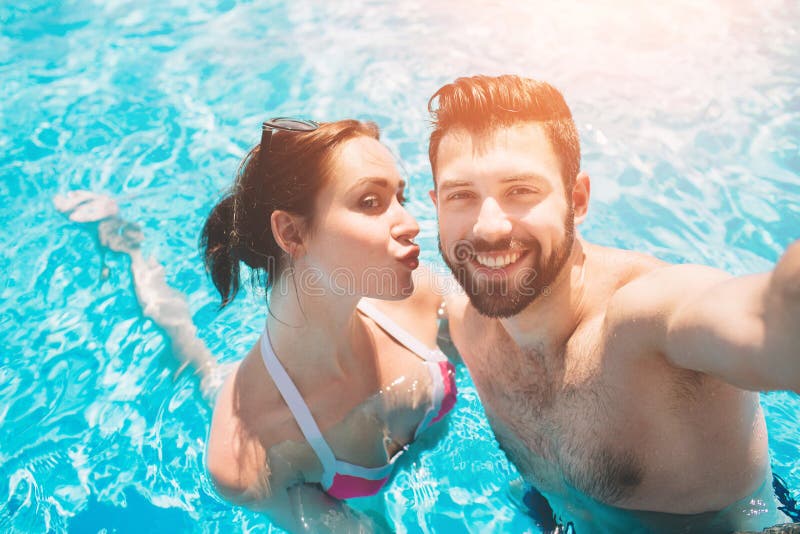 Type gai et dame jeunes se reposant tandis que piscine extérieure Couples dans l'eau Les types font le sephi d'été photos stock Type gai et dame jeunes se reposant tandis que piscine extérieure Couples dans l'eau Les types font le sephi d'été photos stock