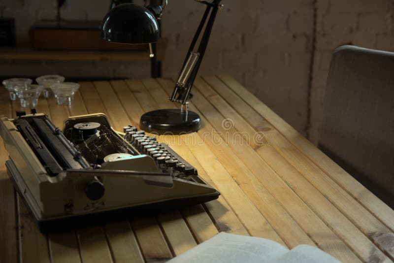 Typewriter Illuminated by a Table Lamp on a Wooden Table Stock Photo